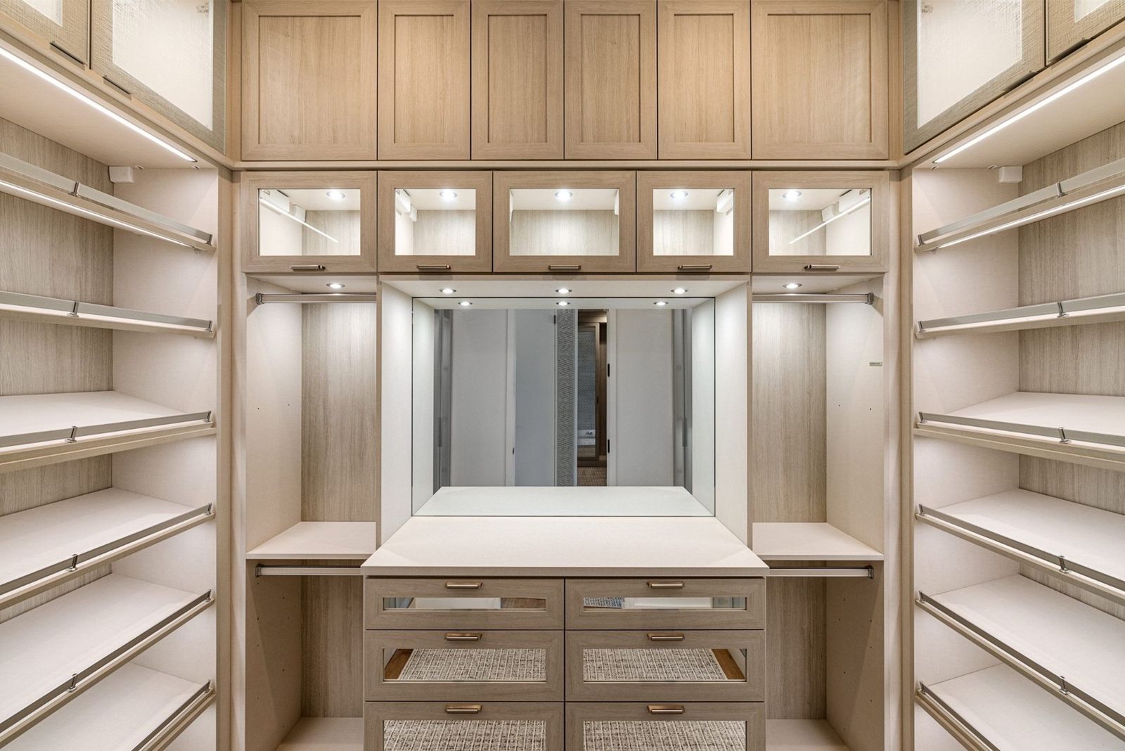 Dressing room closet with lit shelving, glass-front drawers and a center island (example style photo)