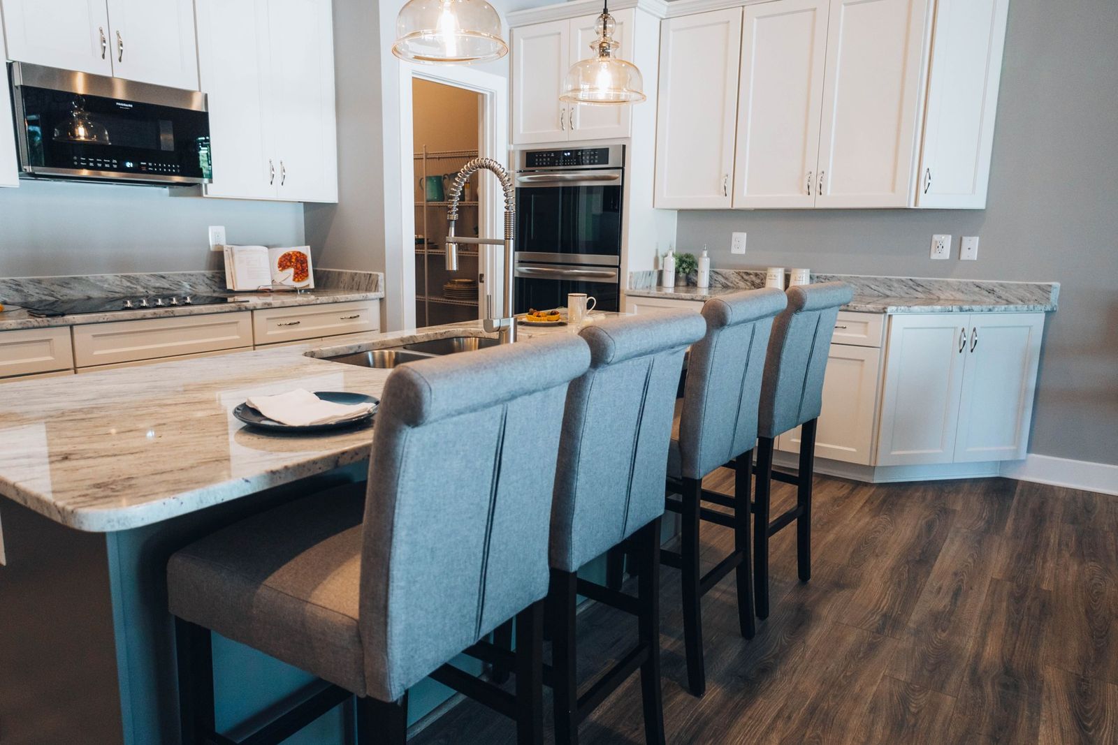 White kitchen with a long island, upholstered bar stools and stone countertops (example style photo)