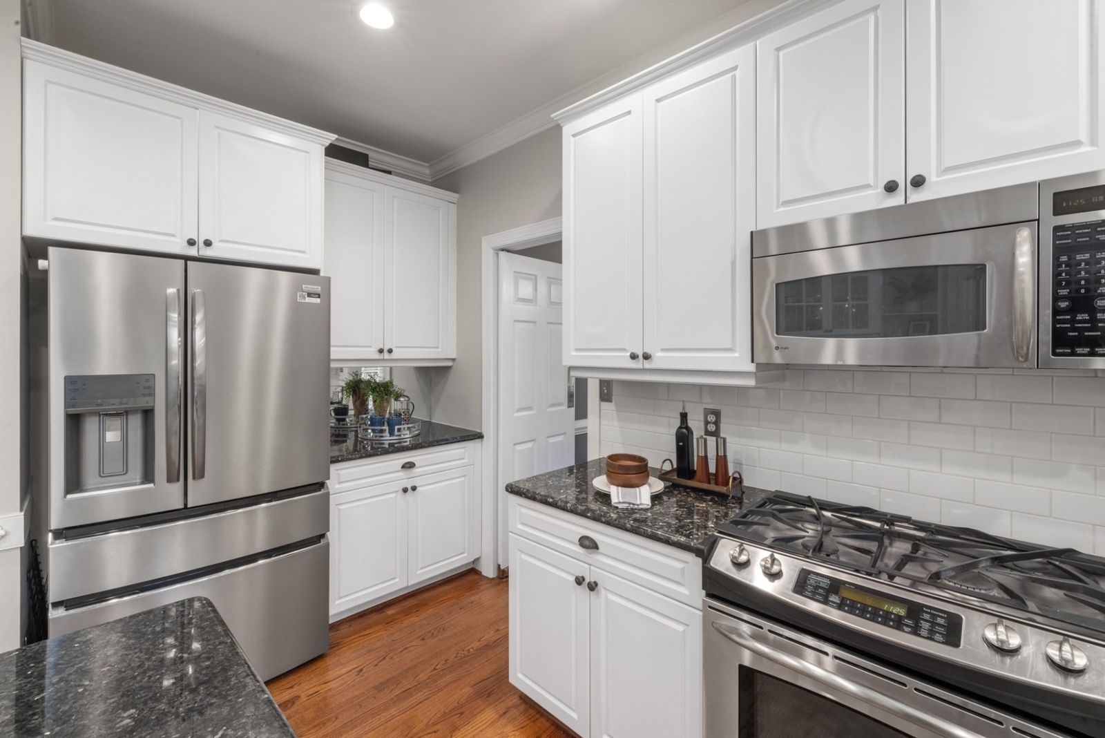 White shaker kitchen cabinets with stainless appliances and a dark granite countertop (example style photo)